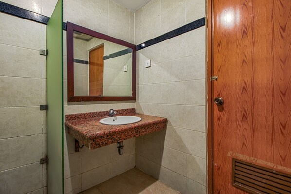 A bathroom with a granite countertop sink, a mirror, and a wooden door. - Plaza 68 Residence (Jakarta)