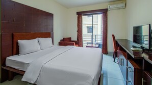 A hotel room with a large bed, a desk with a television, and a window with curtains. - Plaza 68 Residence (Jakarta)