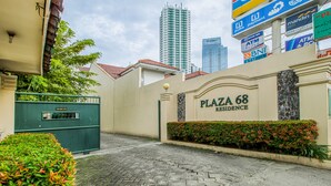 A gated entrance to Plaza 68 Residence with a clear view of the surrounding buildings and a signboard advertising various services. - Plaza 68 Residence (Jakarta)
