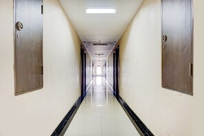 A long, narrow hallway with doors on both sides, leading to a bright end. - OYO 90230 Skyland Bogor Valley (Bogor)