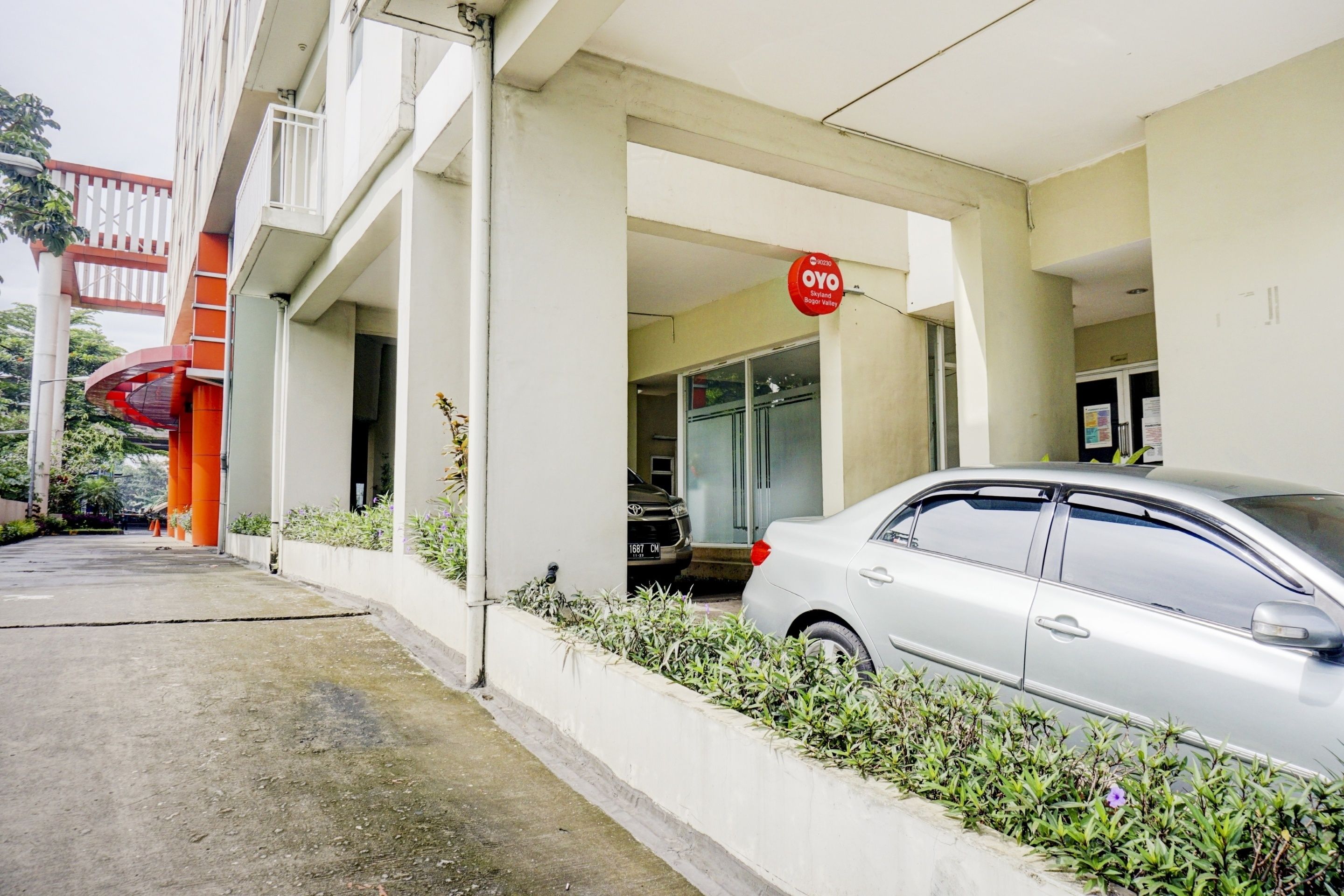 A building with a white facade, a red sign, and a parked car.
