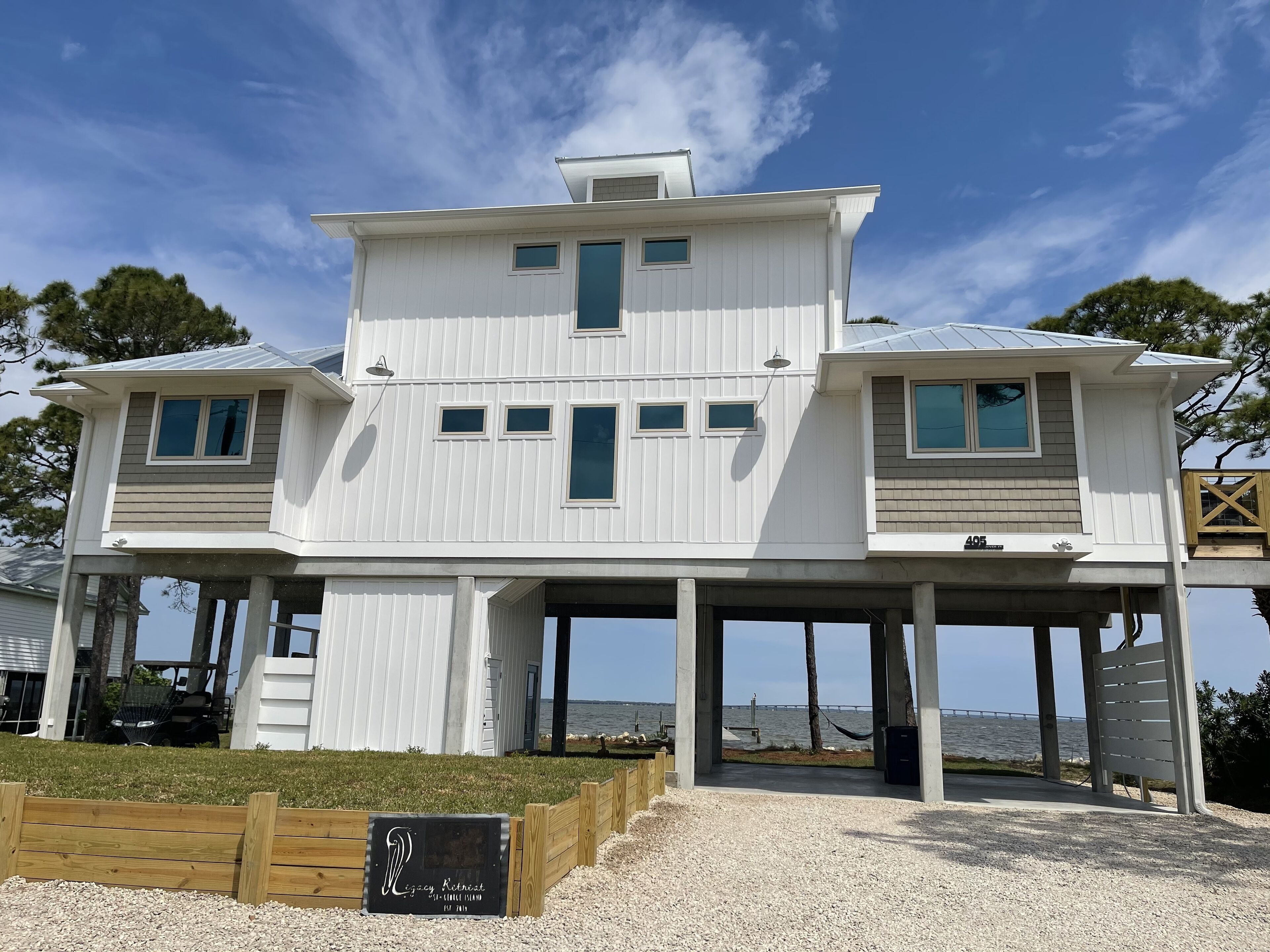 Une maison à deux étages avec une terrasse couverte et vue sur l’eau.