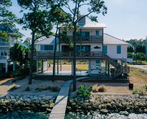 A two-story house with a wooden deck and a staircase leading to a balcony.