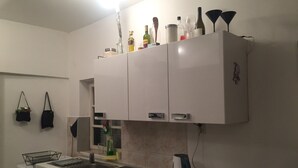 Eine kompakte Küche mit weißen Schränken, einem Geschirrspüler, einer Spüle und einem Wasserkocher auf der Arbeitsfläche.
