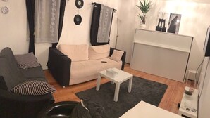 Ein Wohnzimmer mit einer Couch, einem Couchtisch, einer TV-Konsole und einer kleinen Pflanze.