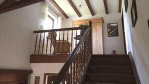 Un escalier en bois, doté d’une rampe, mène à un palier situé au deuxième étage.