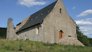 Une église historique en pierre, dotée d’un toit à forte pente, d’une porte en bois et d’un clocher.