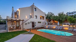 Une maison moderne à deux étages dotée d’une piscine, d’un espace salon extérieur et d’une pergola.