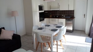 Cozinha moderna com armários brancos, uma mesa de jantar posta para quatro pessoas e um forno preto.