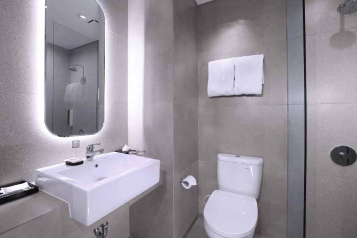 A modern bathroom with a large sink, toilet, and a glass shower enclosure.
