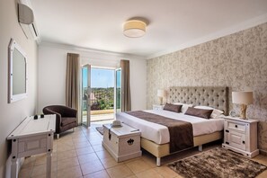 A bedroom with a bed, bedside tables, a chair, a dresser, and a view through a glass door.