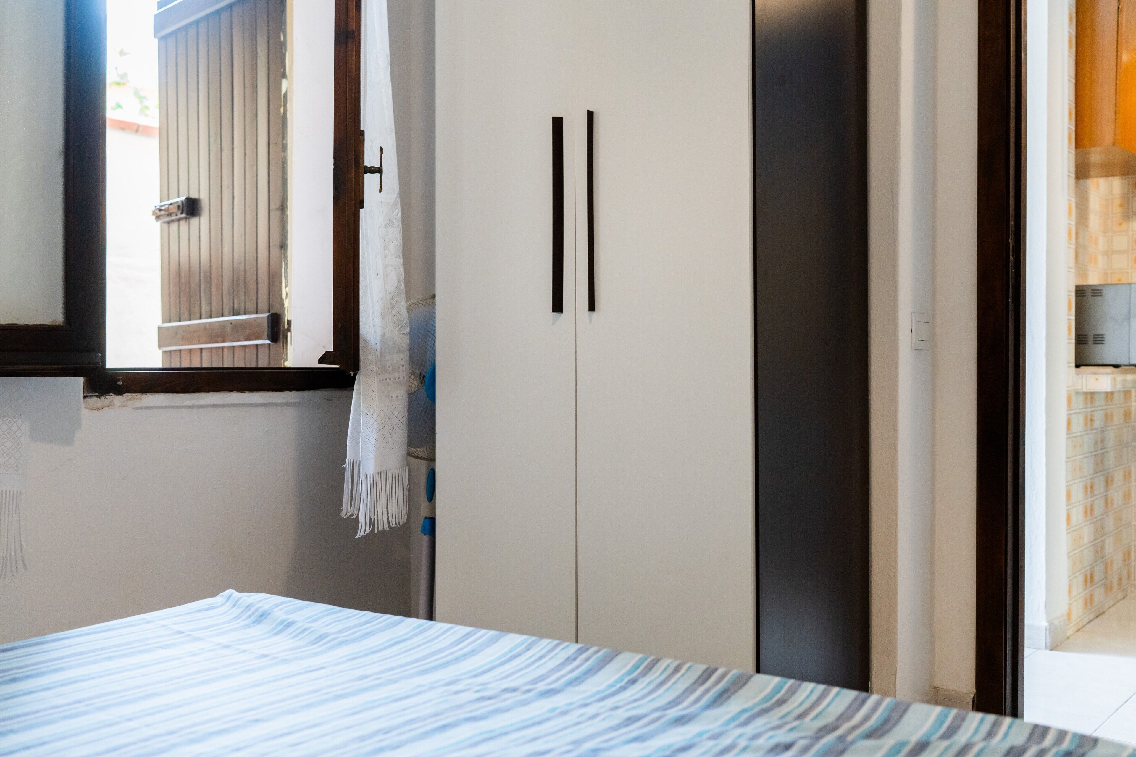 A bedroom with a bed, a wardrobe, and a window with a curtain.