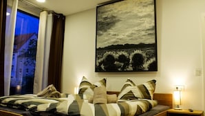 A bedroom with a bed, pillows, a nightstand, and a painting on the wall. - KL17 Ostel – Hostel Döbeln (Doebeln)