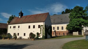 A building with a white facade, a red-tiled roof, and a clock tower. - KL17 Ostel – Hostel Döbeln (Doebeln)