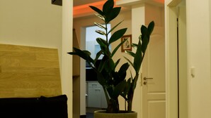 A dining table with a fruit bowl containing apples and oranges, a potted plant, and a wooden headboard. - KL17 Ostel – Hostel Döbeln (Doebeln)