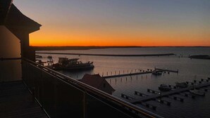 Vista al atardecer desde un balcón con vista a un puerto deportivo con barcos amarrados.