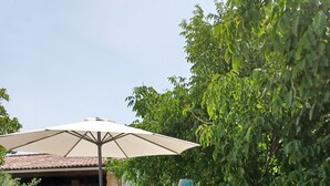 A swimming pool with clear blue water, a white umbrella, and a building in the background. - Refúgio das Artes (Porto de Mos)