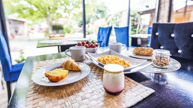 A breakfast setting with croissants, scrambled eggs, and a fruit bowl on a table. - Refúgio das Artes (Porto de Mos)