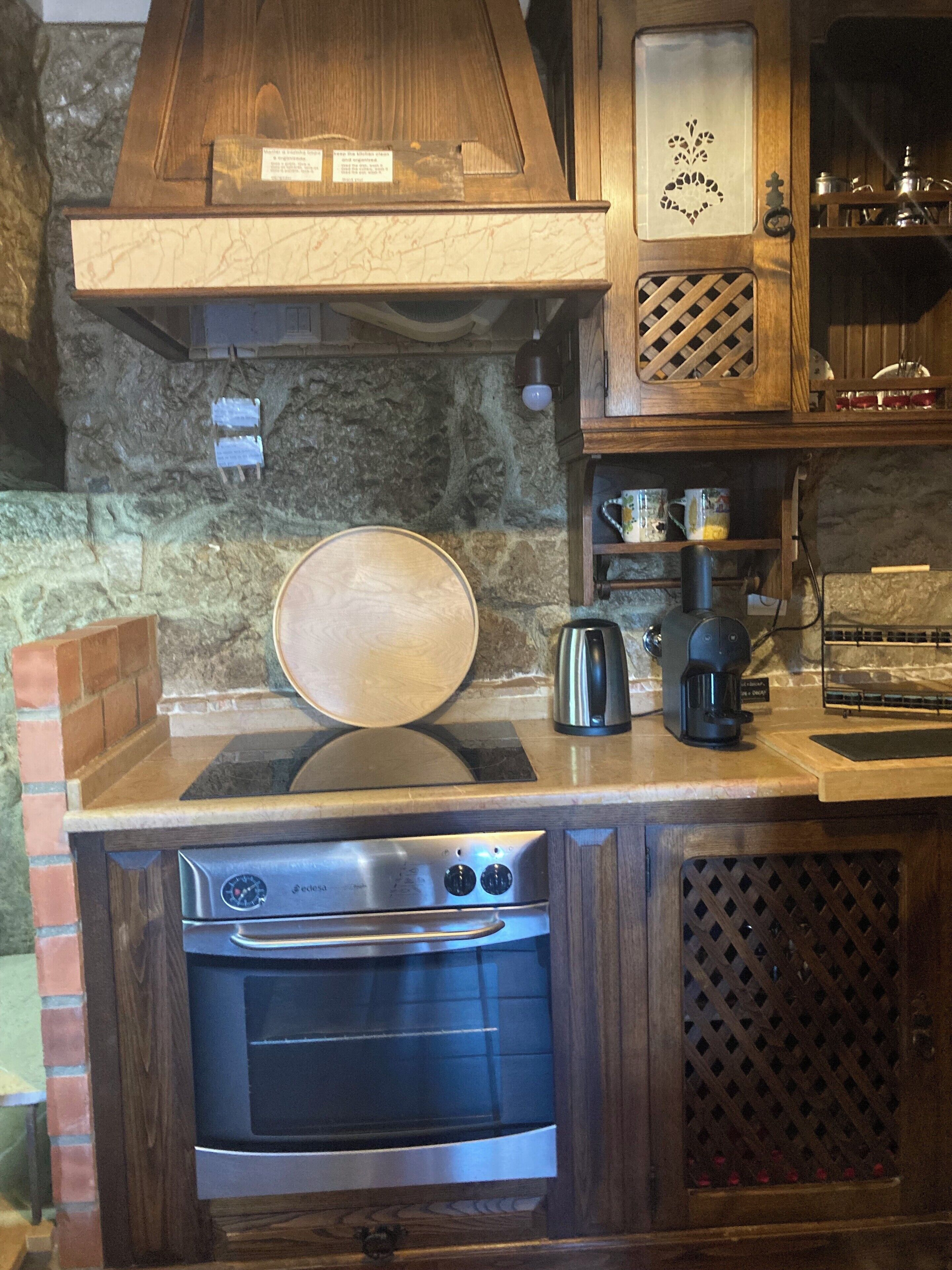 Una cocina con horno empotrado, cafetera y salpicadero de piedra.
