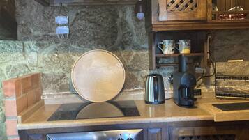 Una cocina con horno empotrado, cafetera y salpicadero de piedra.