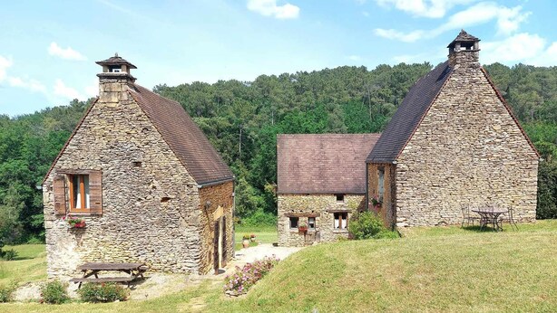 Un edificio de piedra con techo inclinado, una ventana pequeña y un banco de madera afuera.