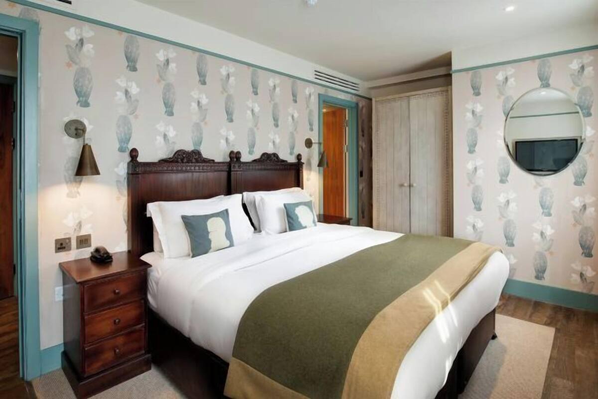 A bedroom with a wooden bed, a bedside table, a nightstand, a mirror, and a wardrobe.