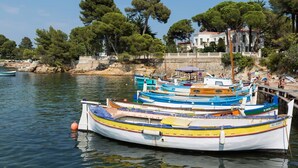A row of colorful boats docked at a marina with a white building in the background. - Superb house with sea view, 3 bedrooms, 3 bathrooms, jacuzzi, sauna, Old Town (Antibes)