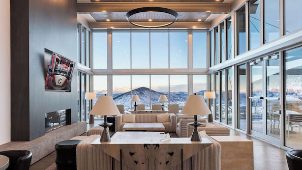 Amplia sala de estar con un ventanal que ofrece vistas a la montaña, chimenea y muebles modernos.