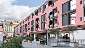 Un edificio rosa con balcones, macetas y un sendero pavimentado.