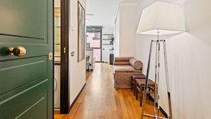 Un pasillo con una puerta verde, un sofá, una lámpara y una escalera.