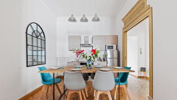 Un espace repas moderne avec une table en bois, des chaises de couleur turquoise et une cuisine en arrière-plan.