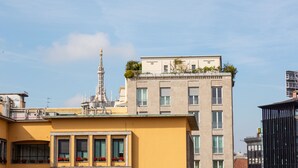 Un immeuble à plusieurs étages doté de balcons, d’une tour et d’un toit plat agrémenté de plantes.
