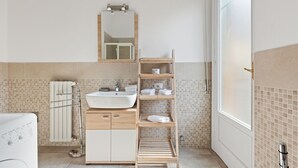 Une salle de bain moderne avec un lavabo, un miroir et des étagères en bois.