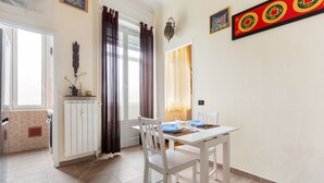 A dining area with a white table and chairs, a window with curtains, and a wall with decorative items. - Gambara Cosy Apartment (Milan)