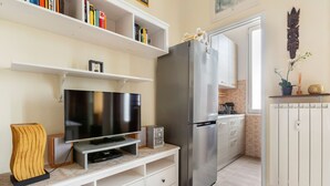 A modern kitchen with a built-in refrigerator, a flat-screen TV, and white cabinetry. - Gambara Cosy Apartment (Milan)
