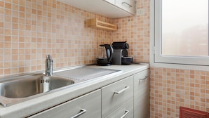 A kitchen with a stainless steel sink, a coffee maker, and a window. - Gambara Cosy Apartment (Milan)
