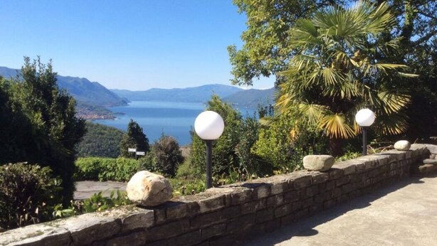 A stone wall with spherical lights, overlooking a scenic view of a lake and mountains. - SUNNY VACATION APARTMENTS IN A QUIET LOCATION WITH A FANTASTIC LAKE VIEW (DUE COSSANI Luino Piemont)