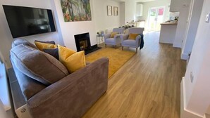 A modern living room with a sofa, armchairs, a fireplace, and a flat-screen TV. - Beautiful Poole House 5 mins to Sandbanks +Netflix (Poole)