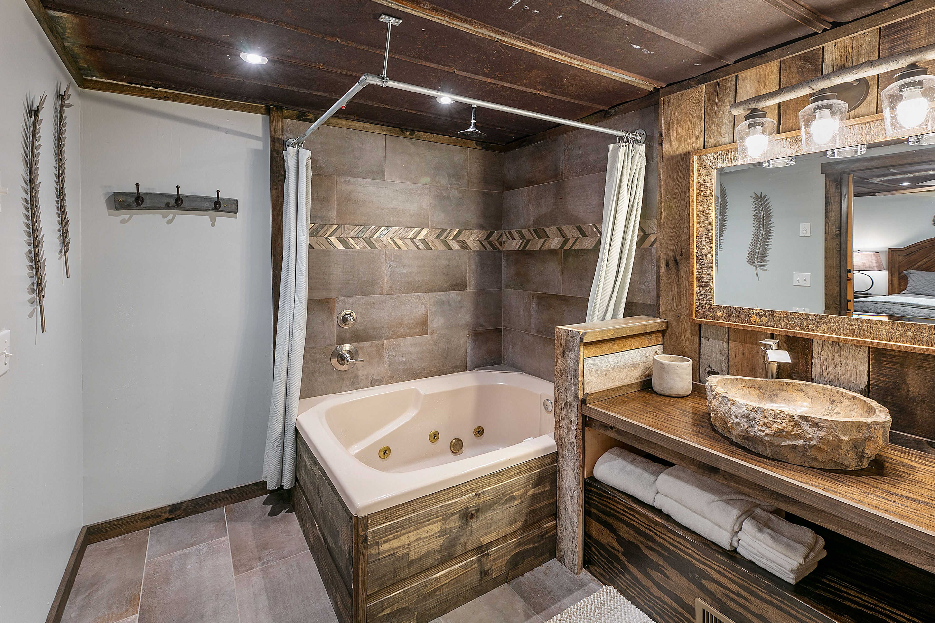 A bathroom with a wooden vanity, a large mirror, and a bathtub.