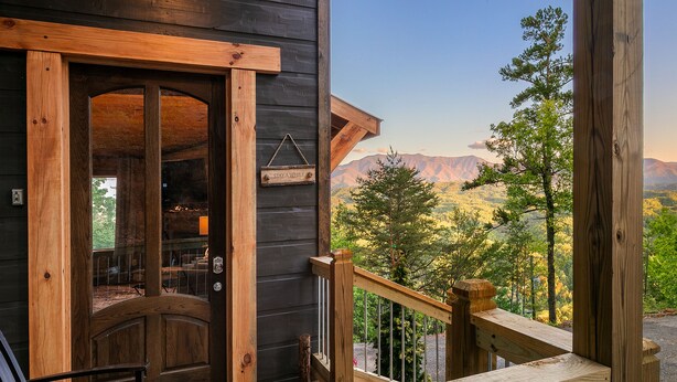 Une cabane en bois dotée d’un balcon donnant sur un paysage montagneux.