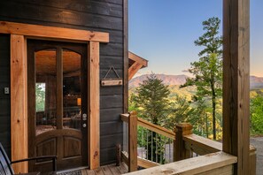 Une cabane en bois dotée d’un balcon donnant sur un paysage montagneux.