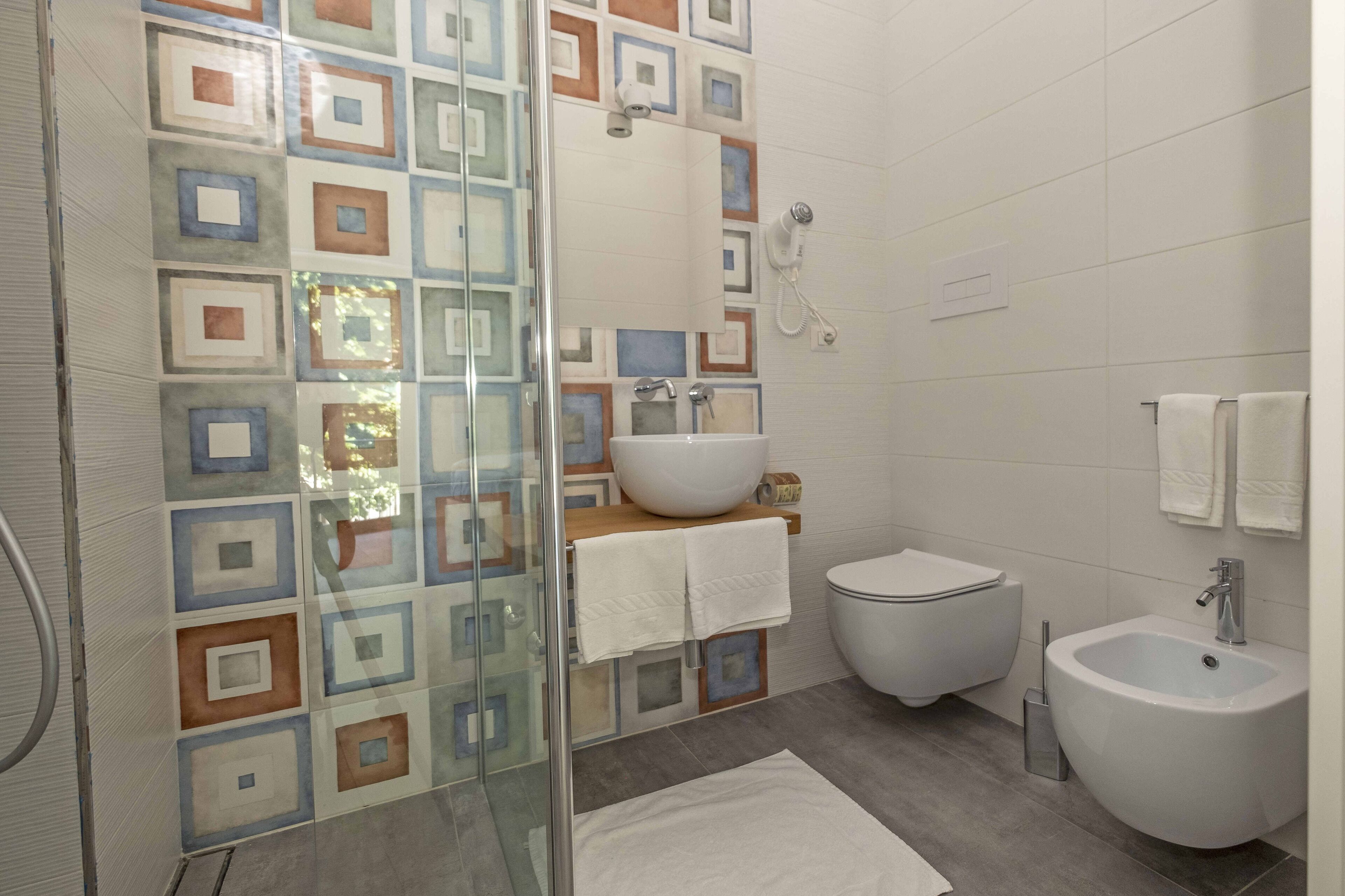 Une salle de bain avec une douche à parois de verre, un lavabo, des toilettes et un bidet.