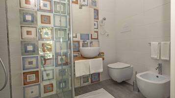 Une salle de bain avec une douche à parois de verre, un lavabo, des toilettes et un bidet.