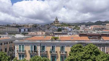 Une vue urbaine avec des bâtiments historiques, une église imposante surmontée d’un dôme, et une colline en arrière-plan.