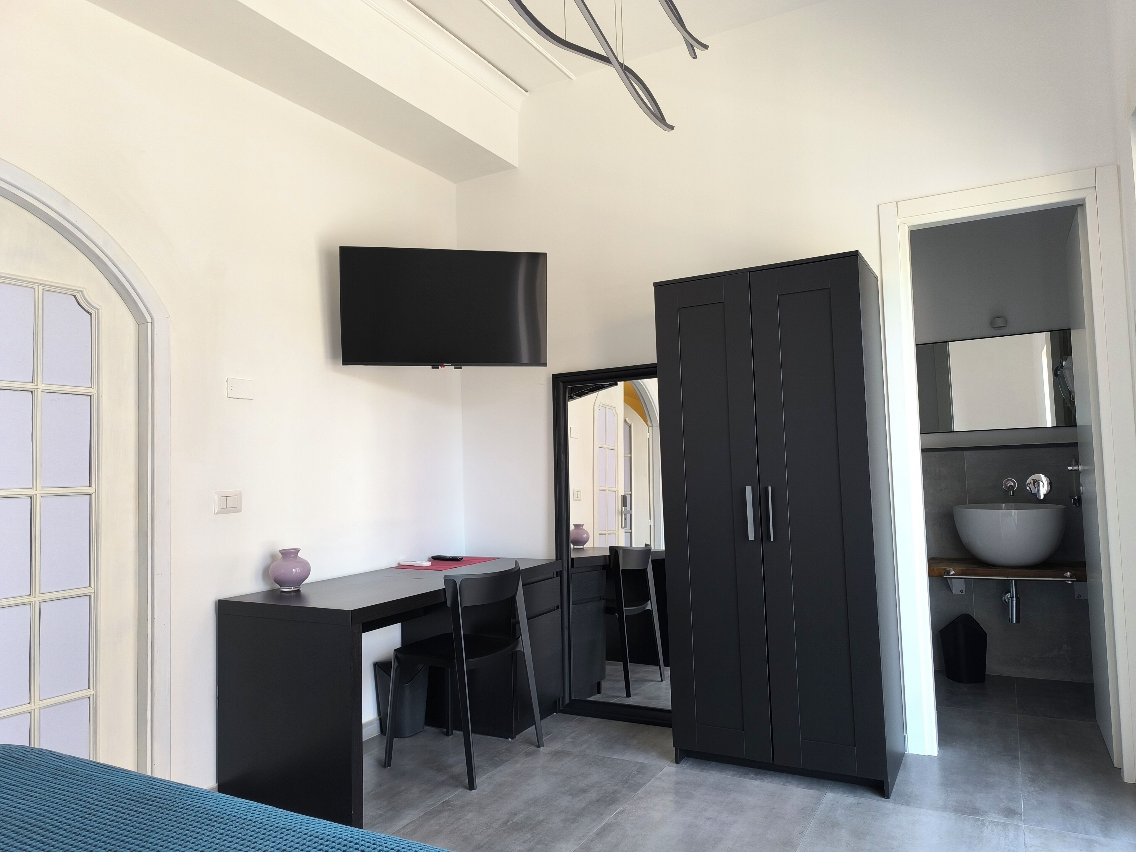 Une chambre à coucher moderne comprenant un lit, un bureau, une chaise, un téléviseur et une armoire.