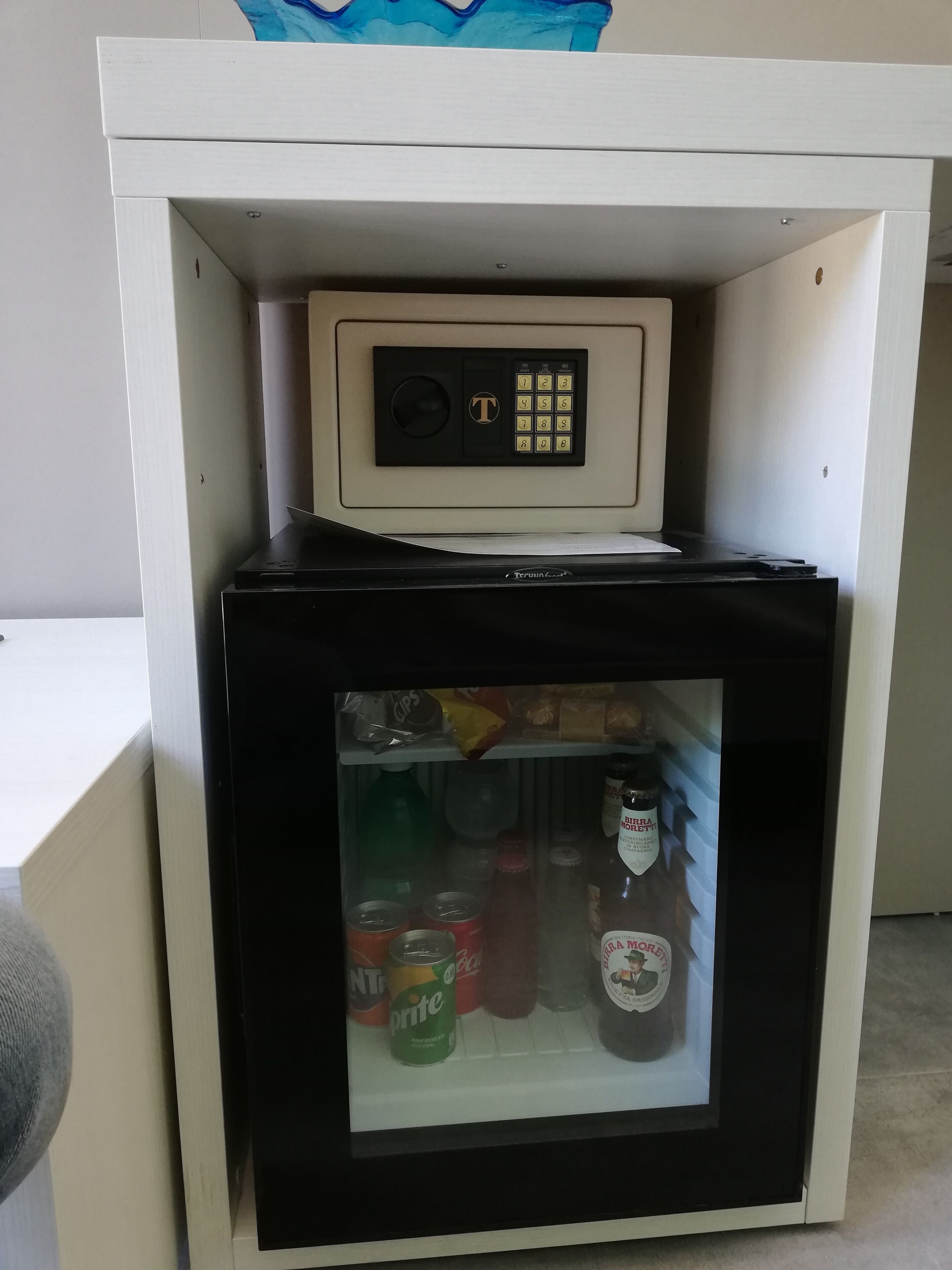 A compact refrigerator with a built-in ice maker, containing beverages and condiments.