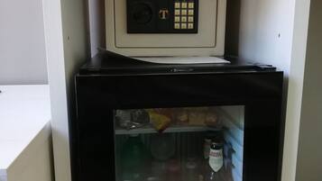 A compact refrigerator with a built-in ice maker, containing beverages and condiments.