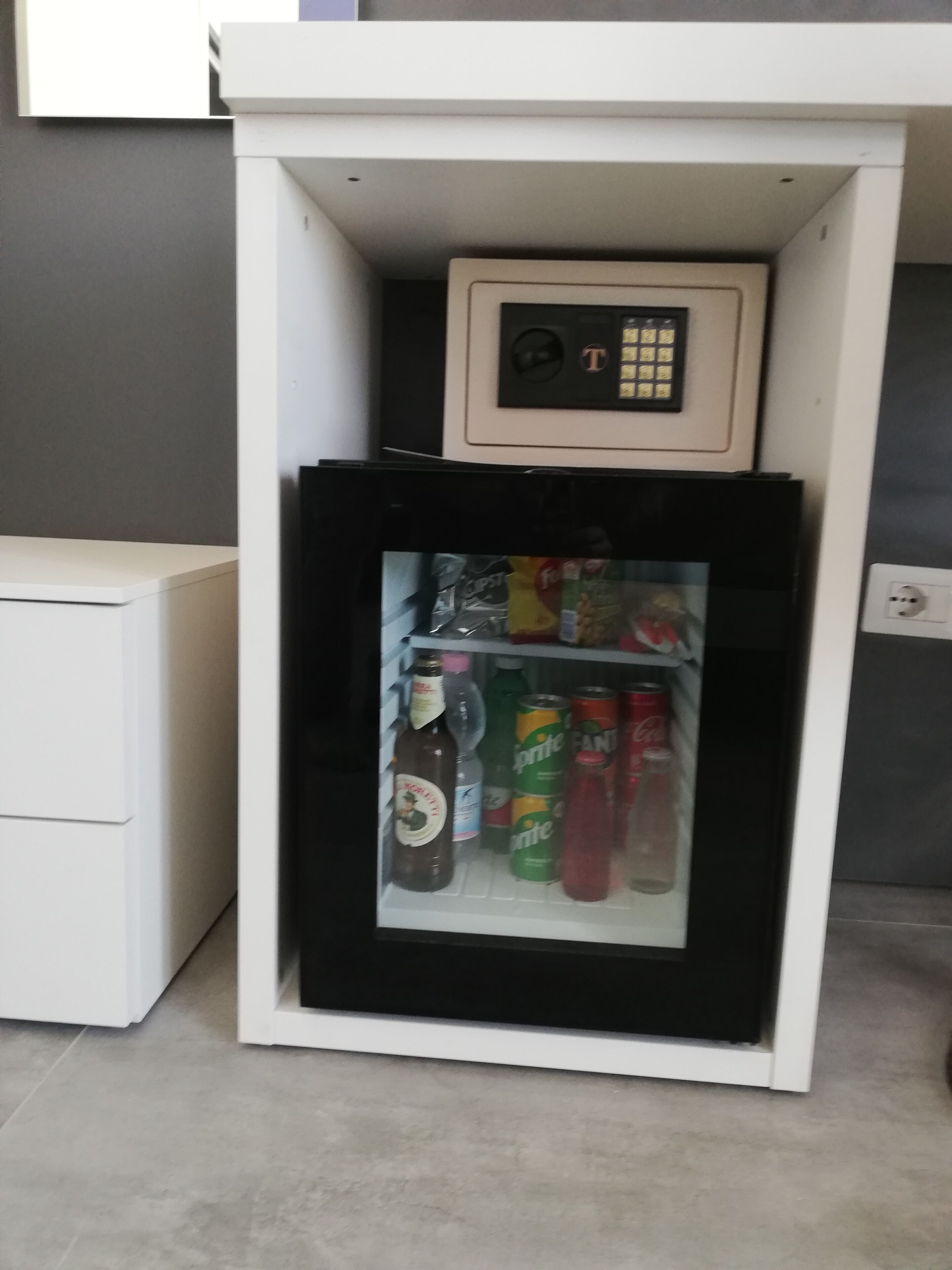 A mini-fridge with a control panel, containing various beverages.