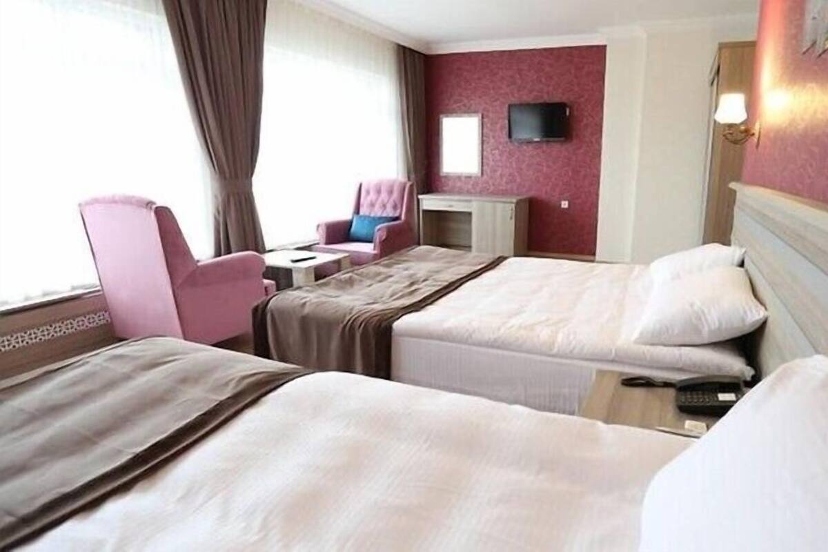 Ein Hotelzimmer mit zwei Betten, einem Schreibtisch, einem Stuhl und einem Fernseher an der Wand.
