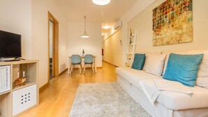 Een moderne woonkamer met een bank, een televisie en een eethoek met stoelen en een tafel.